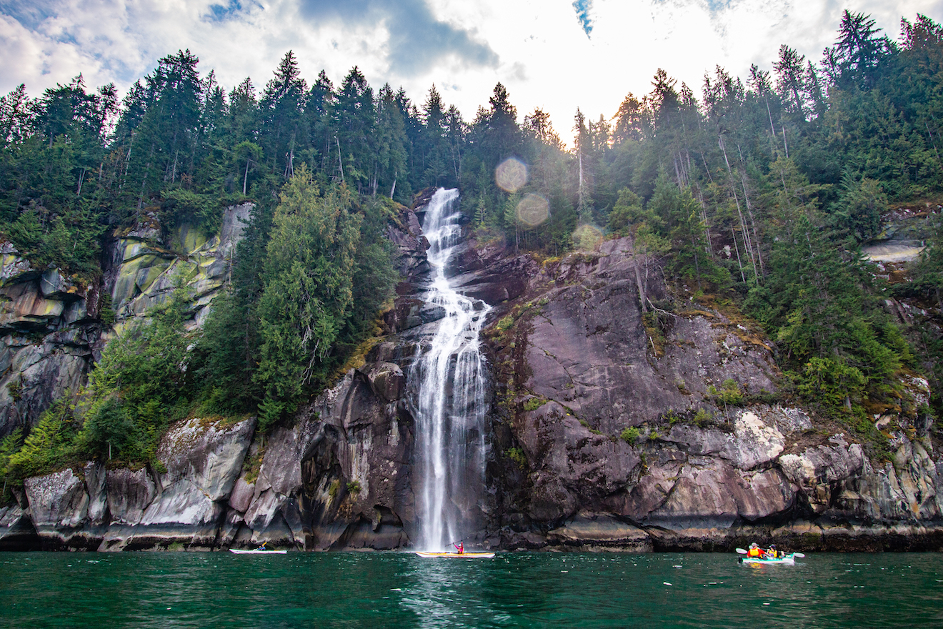 Kayakers approaching a waterfall in Toba Inlet